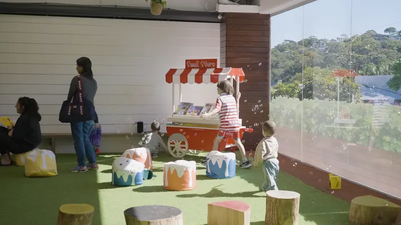 Children at the pretend bakery cart by the windows