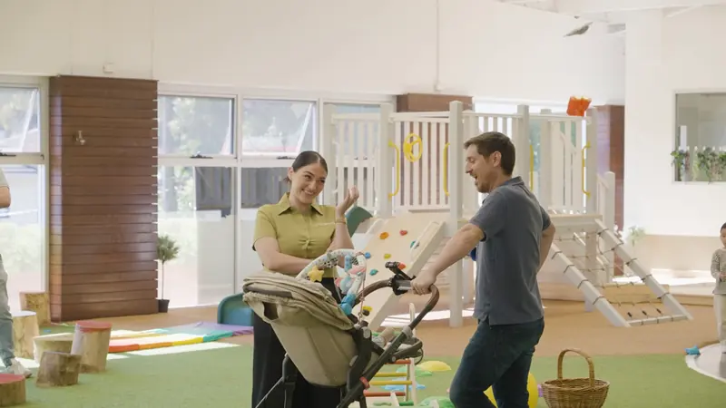 An educator greeting a family with a pram at the play area